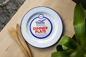 Image shows an enamel dinner plate with bamboo cutlery beside it