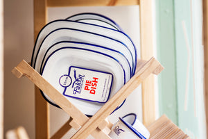 Various sized enamelware dishes on a wooden rack in our shop window display